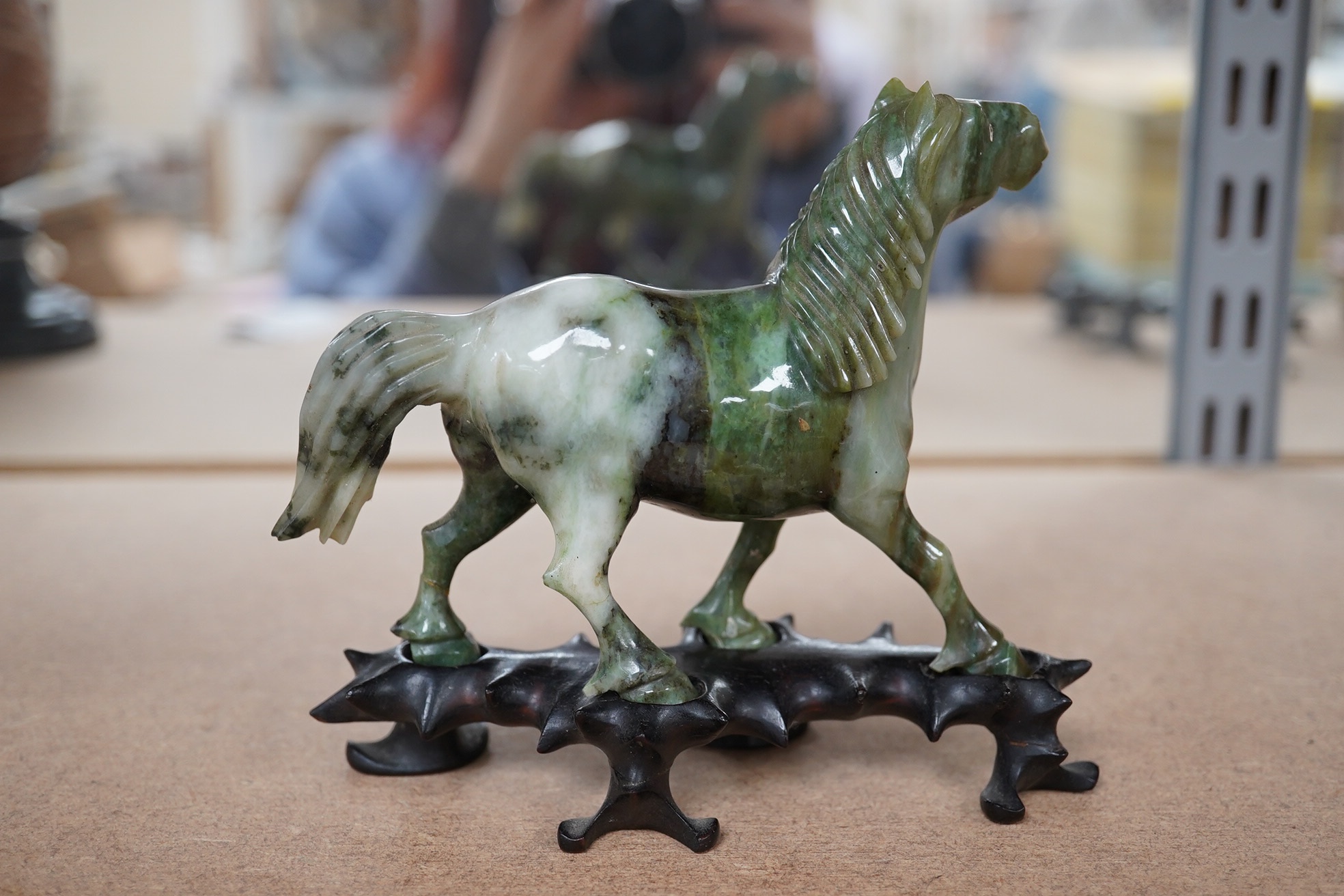 A pair of mid 20th century Chinese jadeite figures of horses, raised on hardwood stands, 13cm wide. Condition - fair, two legs broken and re-glued